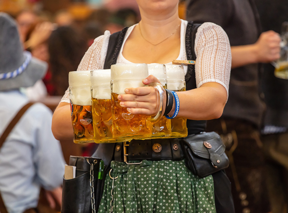 Eine Frau trägt Bierkrüge auf dem Oktoberfest.